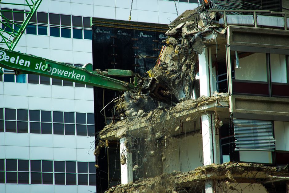 A detailed view of urban building demolition using heavy machinery, showcasing industrial decay.