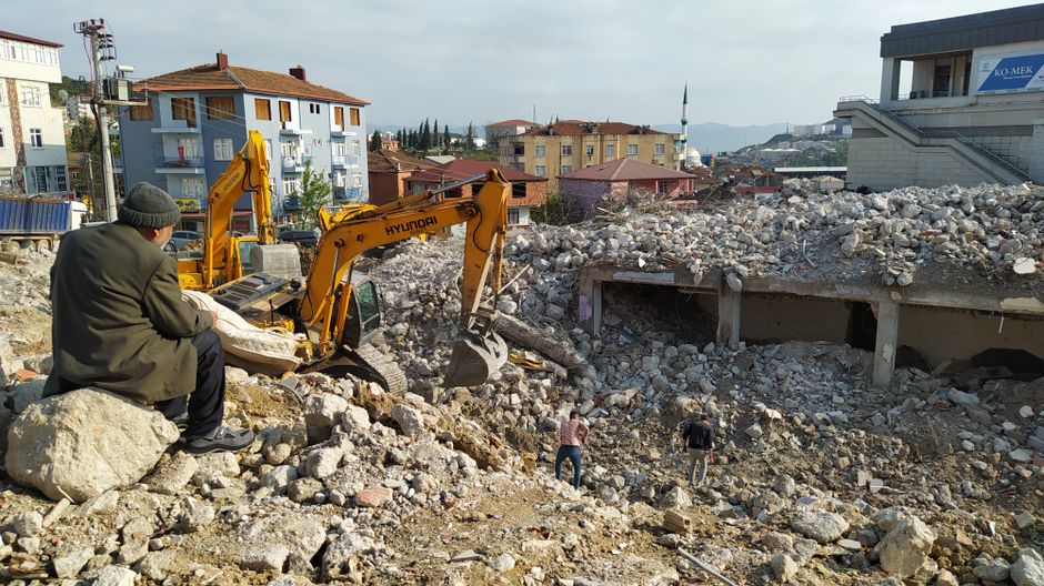 Man watching bulldozers clear building rubble.