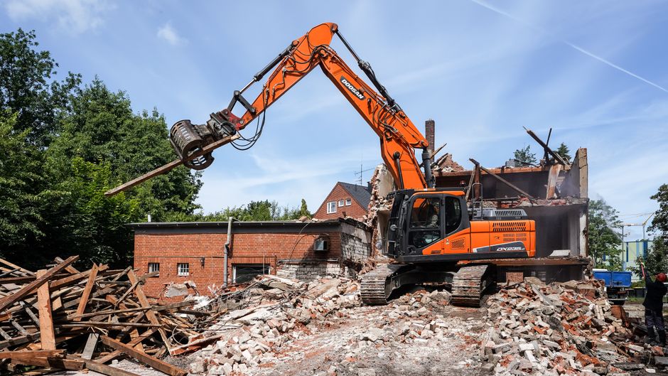 Excavator tearing down a brick building.