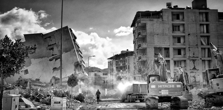 Excavator working among rubble at a demolition site.